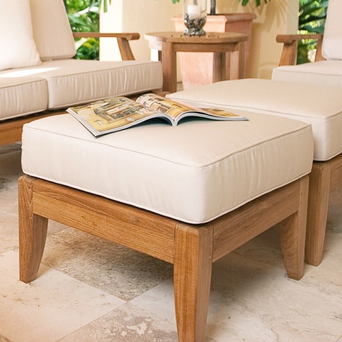 18652 Laguna sofa set on tile patio close up of two cushioned ottomans an opened magazine and side table with candle and background of green shrubs  