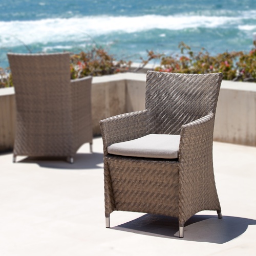 29001SGDP Valencia Summer Grass Armchair showing two on a concrete terrace surrounded by landscape plants with ocean and blue sky background
