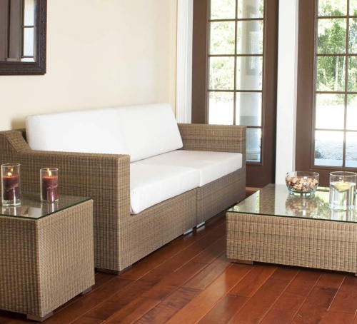 70241 malaga cushioned woven wicker sofa set interior location on wood floors wall mirror glass top tables with two lit pillar candles bowl mixed nuts and floating candle with windows of outside view