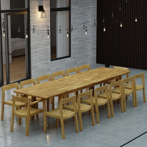 70353 Laguna 15 pc Teak Dining Set on tiled patio in angled side view and hanging patio lights and glass door and privacy fence in background