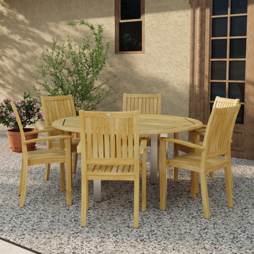 70358 Vogue Sussex 7 pc Dining Set of Vogue 60 inch Round Table and 6 Sussex Armchairs in angled side view on patio with 2 potted plants next to window and french door in background