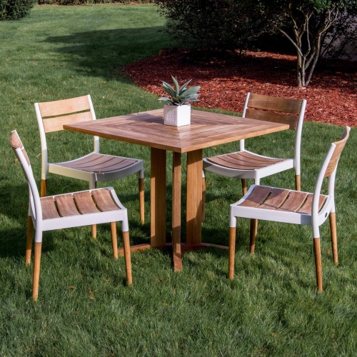 70451 Pyramid Bloom Dining Set of 4 Bloom teak and powder coated aluminum dining side chairs and Pyramid 36 inch square teak dining table with potted plant on grass and trees in back 