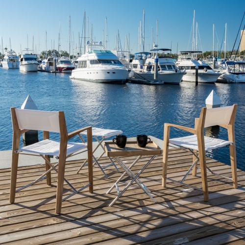 70461 odyssey five piece teak and stainless steel outdoor lounge sets with two coffee cups on table on boat dock viewing boats on water blue sky background