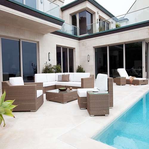 70508 malaga eleven piece woven lounge set next to pool on deck white coffee cup saucer black bowl glass lantern on tables sandals and wrap on chaise windows of home in background