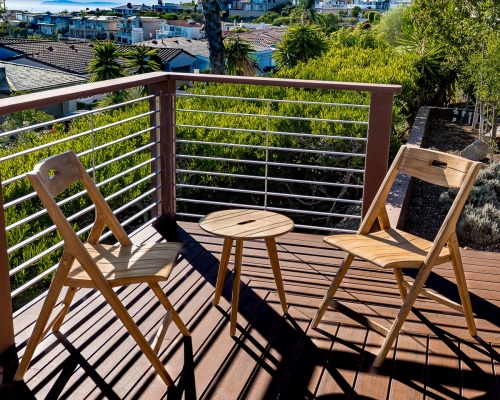 70820 Surf Teak Folding Chairs and Side Table Set of 2 Surf Chairs and Side Table on wood deck with railing overlooking trees and houses in background