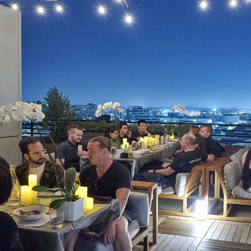 70882 Maya Laguna booth dining set for twelve with people sitting on set  on rooftop patio with dark sky in background