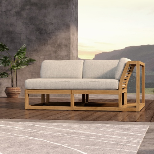 13801DP Maya Left Side Sectional front view on wood floor in front of a partial privacy wall next to a potted plant with hillside in background