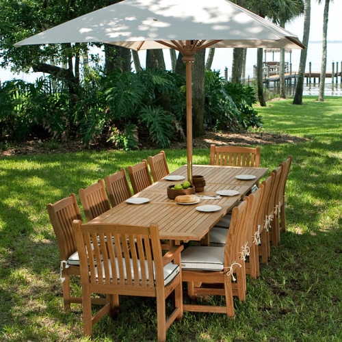 70017 Grand Veranda 13 piece Teak Dining Set with optional canvas rectangular umbrella on grass over looking lake