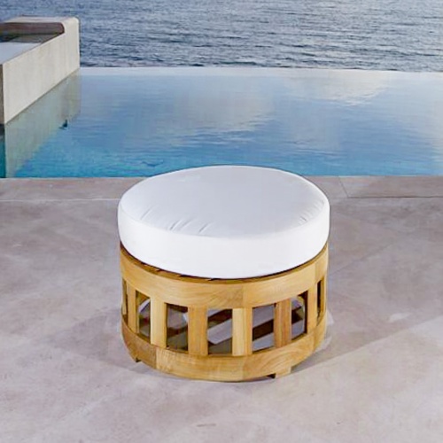 18170 Kafelonia teak coffee table ottoman with Natte Chine colored cushion on concrete patio in front of tall sea grass with the ocean in the background 
