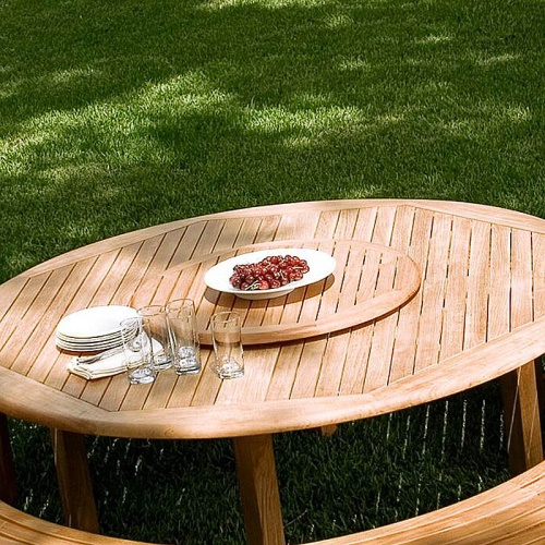18705 round 32 inch teak lazy susan in round dining table with bowl of grapes on table with four glasses plates and napkins on grass lawn