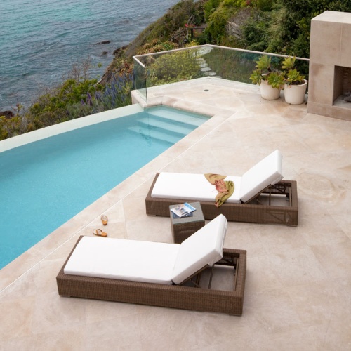 30002dp Malaga synthetic wicker chaise lounger with cushions side profile with magazine lying open on chaise and sandals next to chaise on patio with pool and ocean background