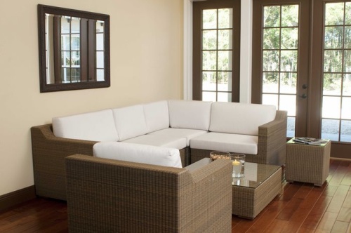 31002 malaga synthetic wicker deep seating collection side view on wood floors wall mirror above sofa floating candle bowl of snacks magazine on table with windows overlooking yard  