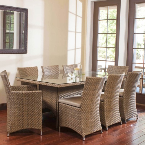 32001SG Valencia Rectangular Wicker Seagrass Table with glass top candles with six side chairs and 2 dining chairs on wood floors with wall mirror in background by patio doors