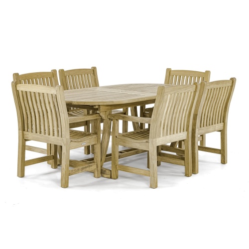 70002 Montserrat 7 piece teak oval Dining Set of Monsterrat Oval Teak Dining Table and 6 Veranda Dining Chairs angled on rock patio surrounded by plants with privacy wall in background