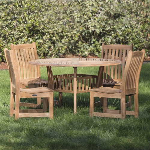 70040 Veranda Hyatt 5 piece teak Dining Set of 4 side chairs and 48 inch round dining table on grass lawn with concrete walkway and mulched landscaped area in background