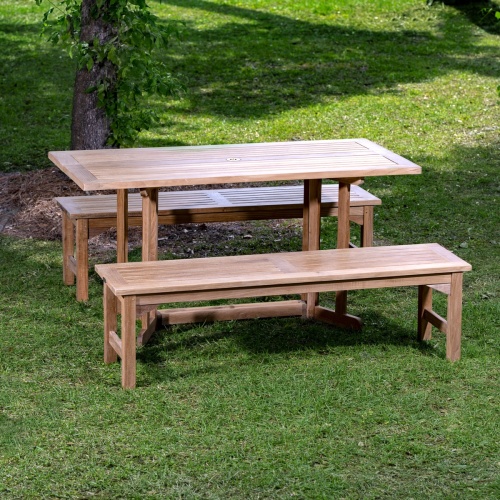 70061 Barbuda Picnic Table teak Dining Set on grass field and white bowl of whole fruit and plate of french bread on table with lake and dock in background