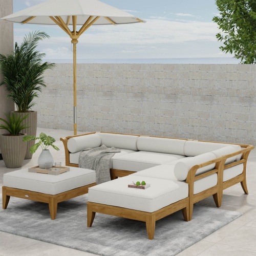 70121 Aman Dais 6 piece teak sectional set next to a wall and railing on wood patio with ocean and blue sky in background