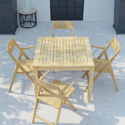 70147 Surf teak 36 inch square 5 pc Dining Set of 4 teak folding Dining Chairs and a teak 36 inch square dining table in angled aerial view on stone patio with windows in background