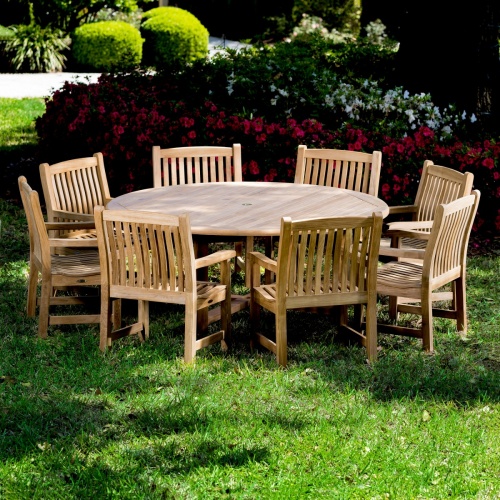 70173 Buckingham teak 9 pc Dining Set with optional seat cushions and optional lazy susan in table center on grass lawn with flowers and tree in background