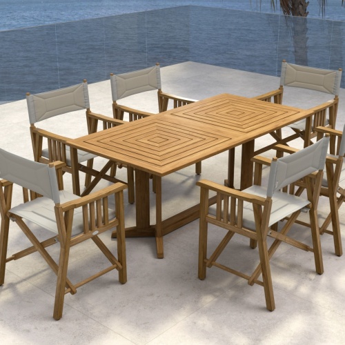70360 Pyramid Director 7 piece teak Dining Set of 6 teak Director Chairs and Pyramid Teak Dining Table angled aerial view on stone patio with potted palm and ocean in background