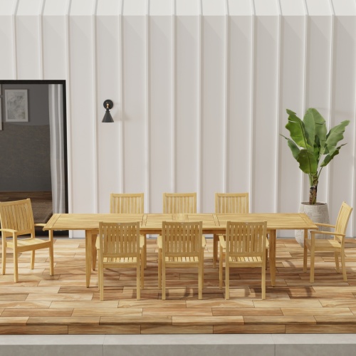  70774 Laguna Sussex 9 pc Teak Dining Set with optional umbrella in side view on patio with potted tree and glass door of house in background