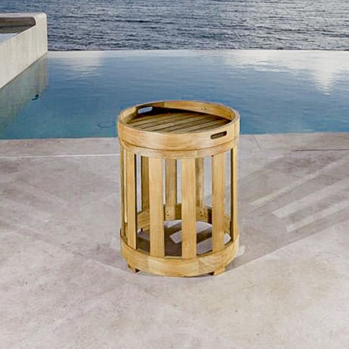 70873 Kafelonia teak side table with removable teak serving tray on concrete patio in front of infinity pool overlooking ocean in background