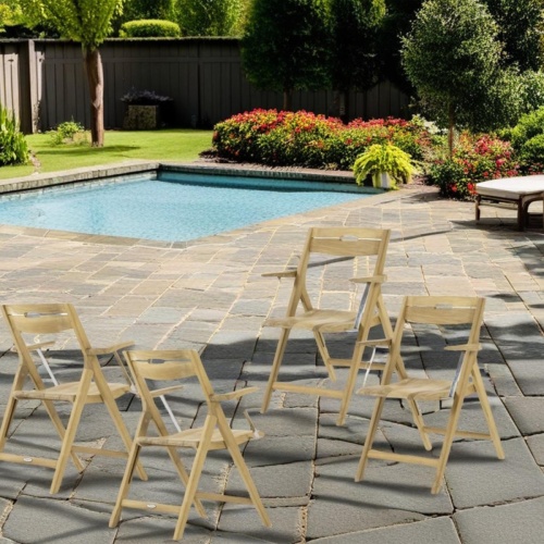 70888 Surf Dining Chair Set of 4 on stone pool deck surrounded by plants and trees with a pool and fence in the background
