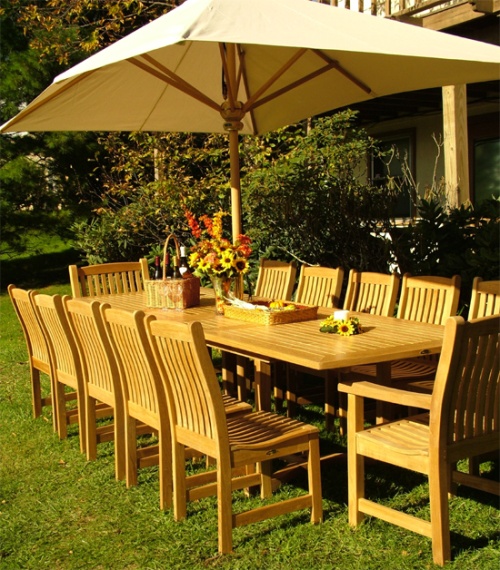 11315RF Veranda teak dining side chair with seat cushions with Veranda dining set showing optional open market umbrella on grass lawn and palm trees in back