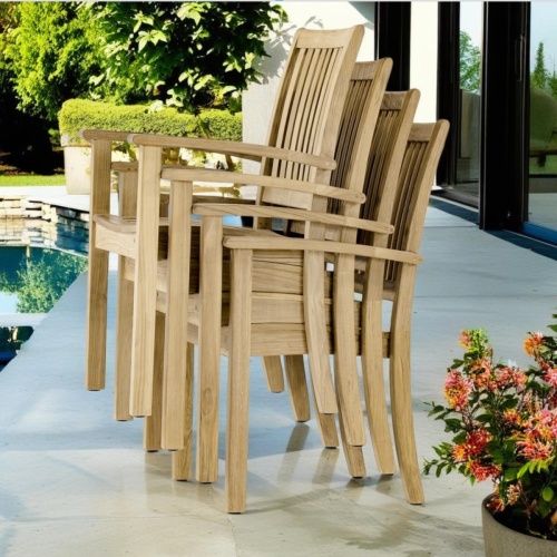 12196ST Sussex Dining Chair showing 4 stacked high angled side view on pool deck next to pool with plant edge and house glass slider in background  