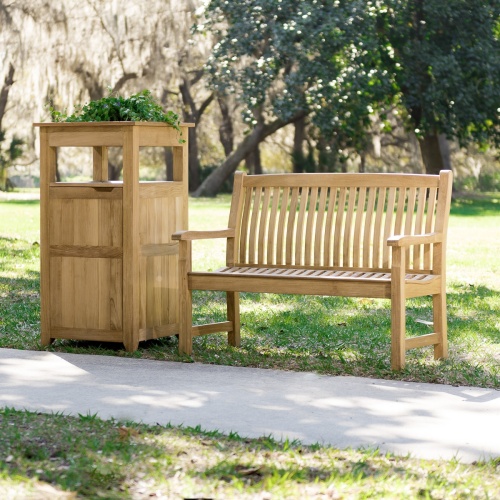 13218 Veranda Teak 4 foot Bench on grass field with garden in front and trees in background