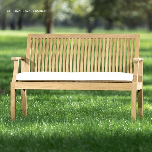 13810 Laguna 4 foot Teak Bench with optional seat cushion side angled on grass field with trees in background