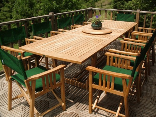 70006 Veranda teak 11 piece director chair dining set potted violet plant on teak lazy susan on teak floor deck with trees in background