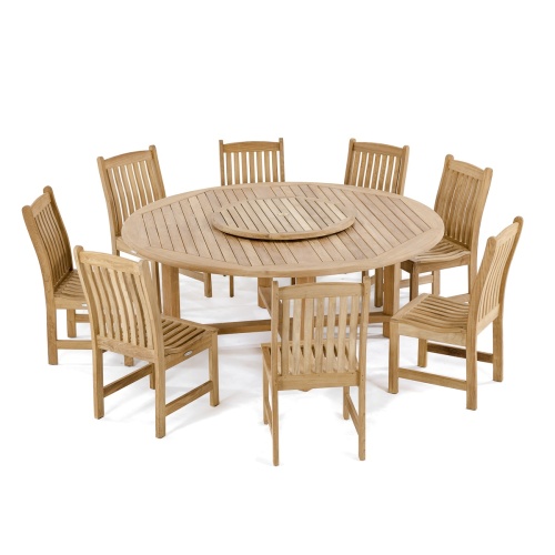 70020 Buckingham Veranda 9 piece teak round dining set with optional seat cushions on grass with flowering shrubs trees and landscaping plants with yellow house in background