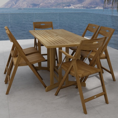 70146 Surf Nevis Teak 7 pc Dining Set of Nevis Dining Table and 2 Surf Dining Chairs and 4 Surf Side Chairs angled end view on tile patio overlooking the ocean and land mass in background