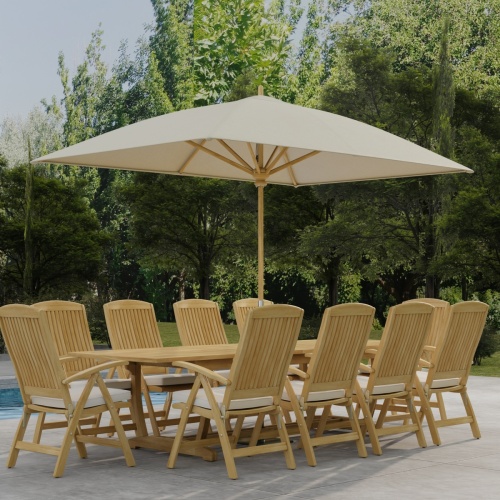 70205 Reclining 11 pc Teak Dining Set with optional umbrella and seat cushions on pool deck in angled corner view with trees and plants in background