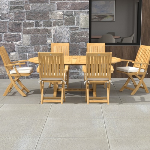 70368 Martinique Oval Barbuda Chair 7 pc Dining Set of Martinique Oval Table and 6 Barbuda Teak Arm Chairs in side view on patio with stone house in the background