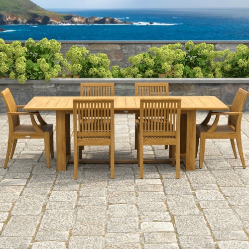 70377 Horizon Laguna 7 pc Teak Dining Set of Horizon Dining Table and 2 Laguna DIning Arm Chairs and 4 Laguna Side Chairs on paver pergola patio with landscaping plants and hillside in the background 