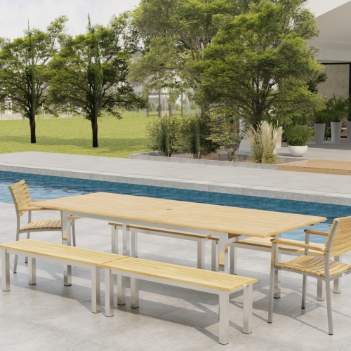 70440 Vogue 7 piece Teak and Stainless Steel Picnic Set in angled side view in front of a pool with landscape plants and trees in the background