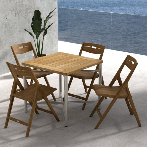 70450 Surf Odyssey Folding Dining Set of Odyssey Bistro Table and 4 Surf Side Chairs in angled aerial view on a stone patio with the ocean and blue sky in the background