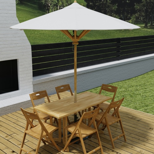 70472 Surf Nevis Teak 7 pc Dining Set with optional umbrella in  side view on wood deck in front of an outdoor fireplace and fence and hillside in background