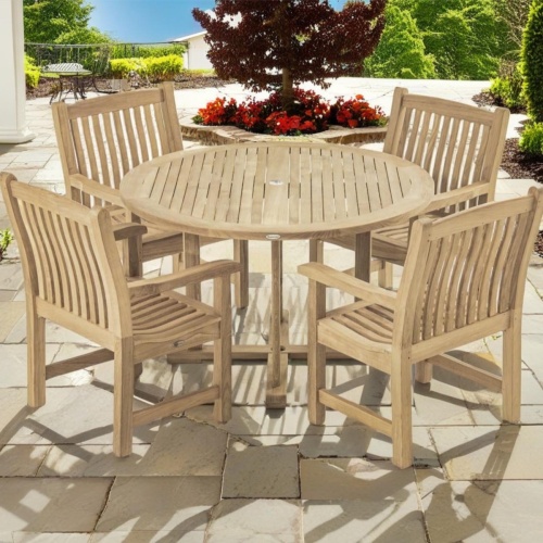 70483 Veranda teak 4 ft Round Dining Set of 4 Veranda Teak Armchairs and 4 foot round teak dining table on stone patio with plants and trees in background 