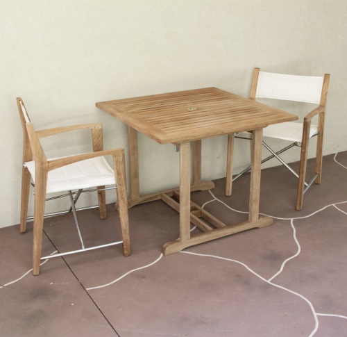 70651 Odyssey 3 piece Square Dinette Set of 2 folding director chairs and a teak 36 inch square dining table on patio against a wall