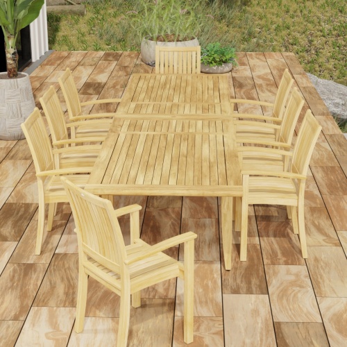 70774 Laguna Sussex 9 pc Teak Dining Set of Grand Laguna Table and 8 Sussex Armchairs in end view on patio with potted plants and grass area in background
