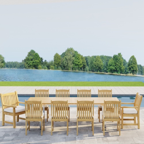 70826  Vogue Veranda 13 pc Teak Dining Set with optional seat cushions showing side profile view on patio in front of a pool with a lake and trees in background