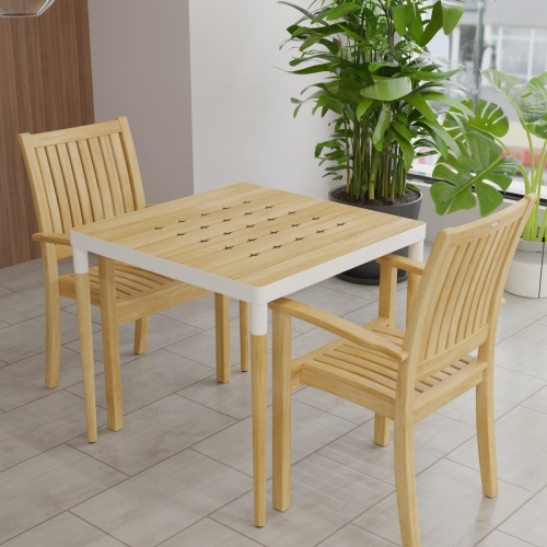 70907 Bloom Sussex 3 pc Dining Set of a Bloom Teak & Powder Coated Aluminum Square Table and 2 Sussex Armchairs corner view on tiled floor with 2 plants and windows in background