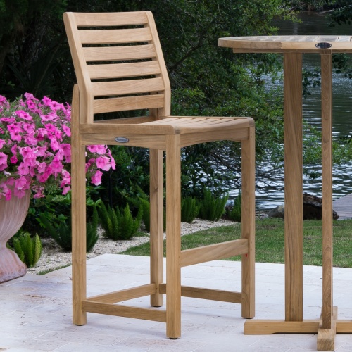 11812 Somerset Side Barstool on concrete patio potted flowering plant next to stool with lake and trees in background