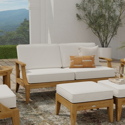 13152dp laguna teak loveseat collection set in front view on outdoor patio with 2 throw pillows and potted tree and landscaped background
