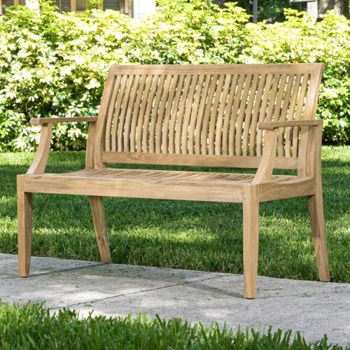 13810 Laguna 4 foot Teak Bench with optional seat cushion front view on grass field with trees in background