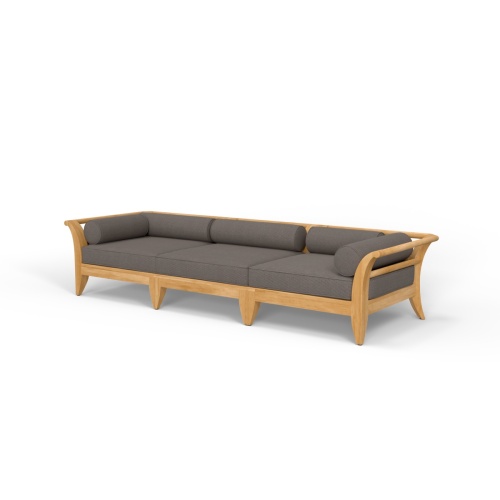 thumbnail image of 70102 Aman Dais 3 pc Sofa Set cushioned with magazine and two optional ottomans with plate of pears on teak tray set on patio with fireplace two plants grass and treed background 