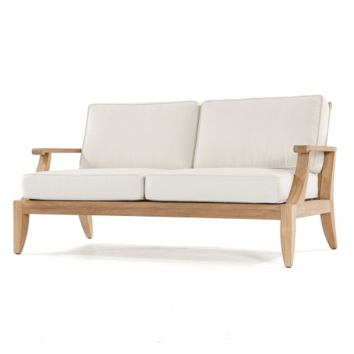 70105 Laguna 7 pc 66 inch Sofa Set on patio with pillar candle and glass holder on side table open magazine on ottoman potted palm tree in corner landscape and house in background